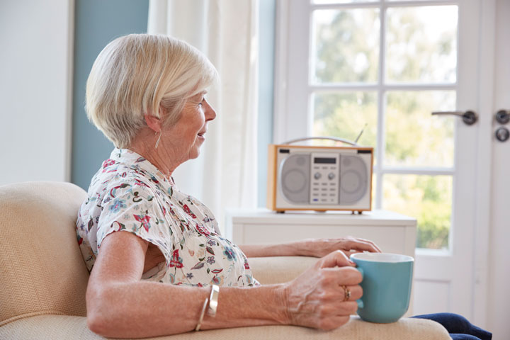 senior-woman-drinking-tea-and-listening-to-radio-PN5U2P7